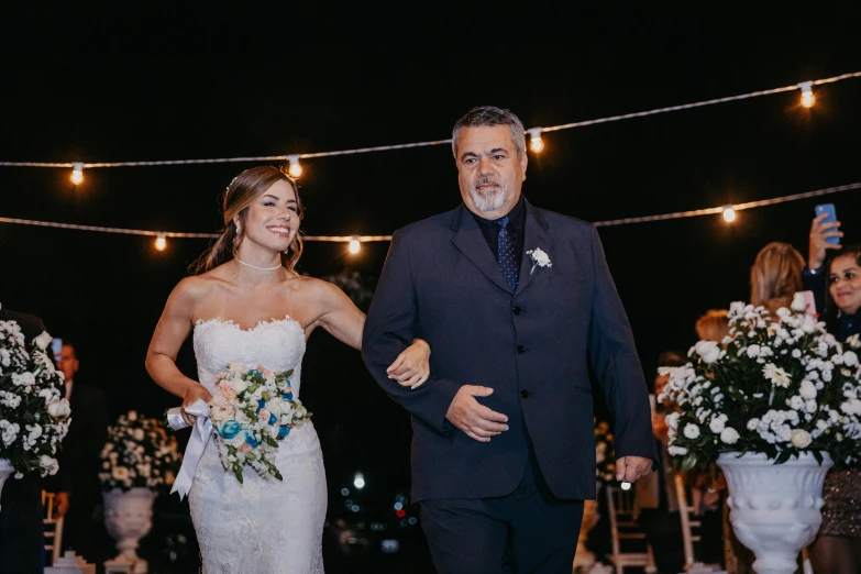 a couple walking down a aisle with flowers