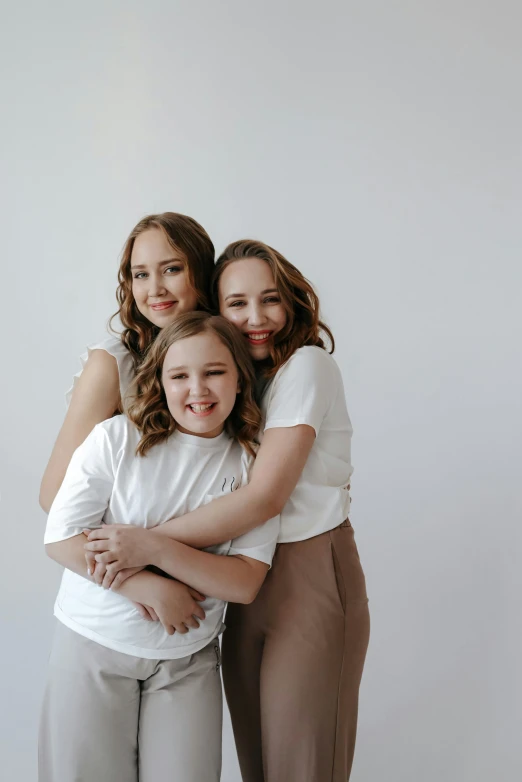 three female friends cuddling together smiling and posing