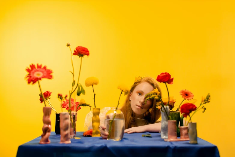 a woman leaning over a table with several vases filled with flowers