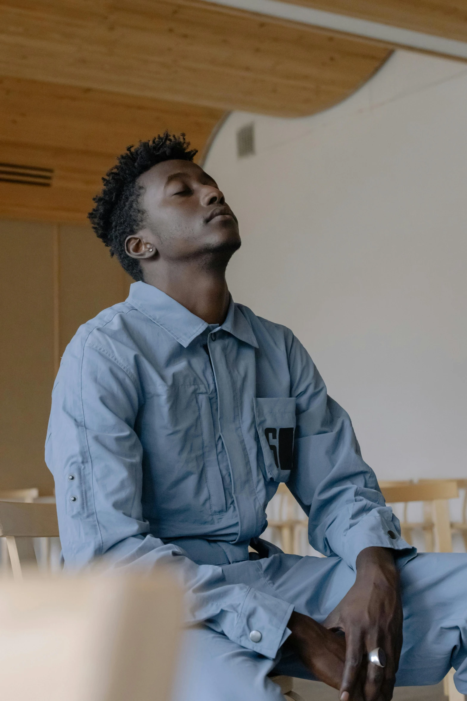 a black man sitting down wearing a blue shirt