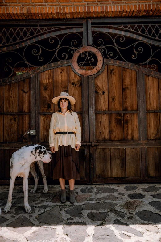 a girl stands near a horse next to an old barn