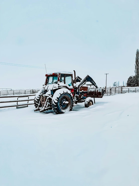 a tractor in a field on a snow covered day