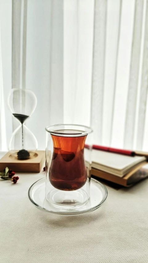 a tea cup on a plate next to an hourglass