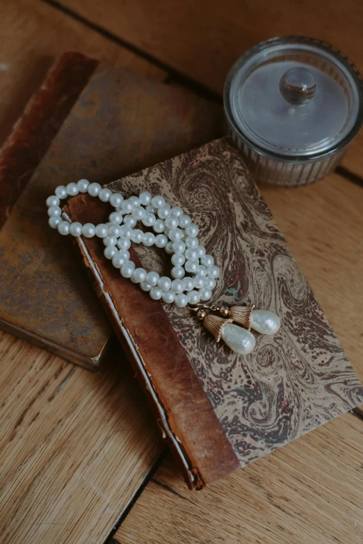 a pearls necklace sitting on a book on the ground