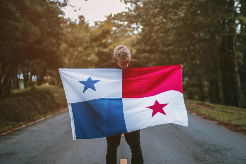 a man walks on the road holding a flag