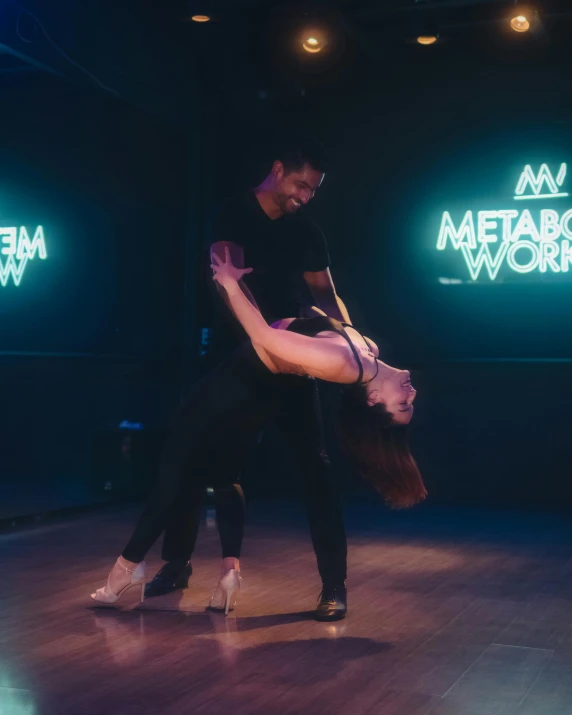 the couple is doing a dance in front of neon signs