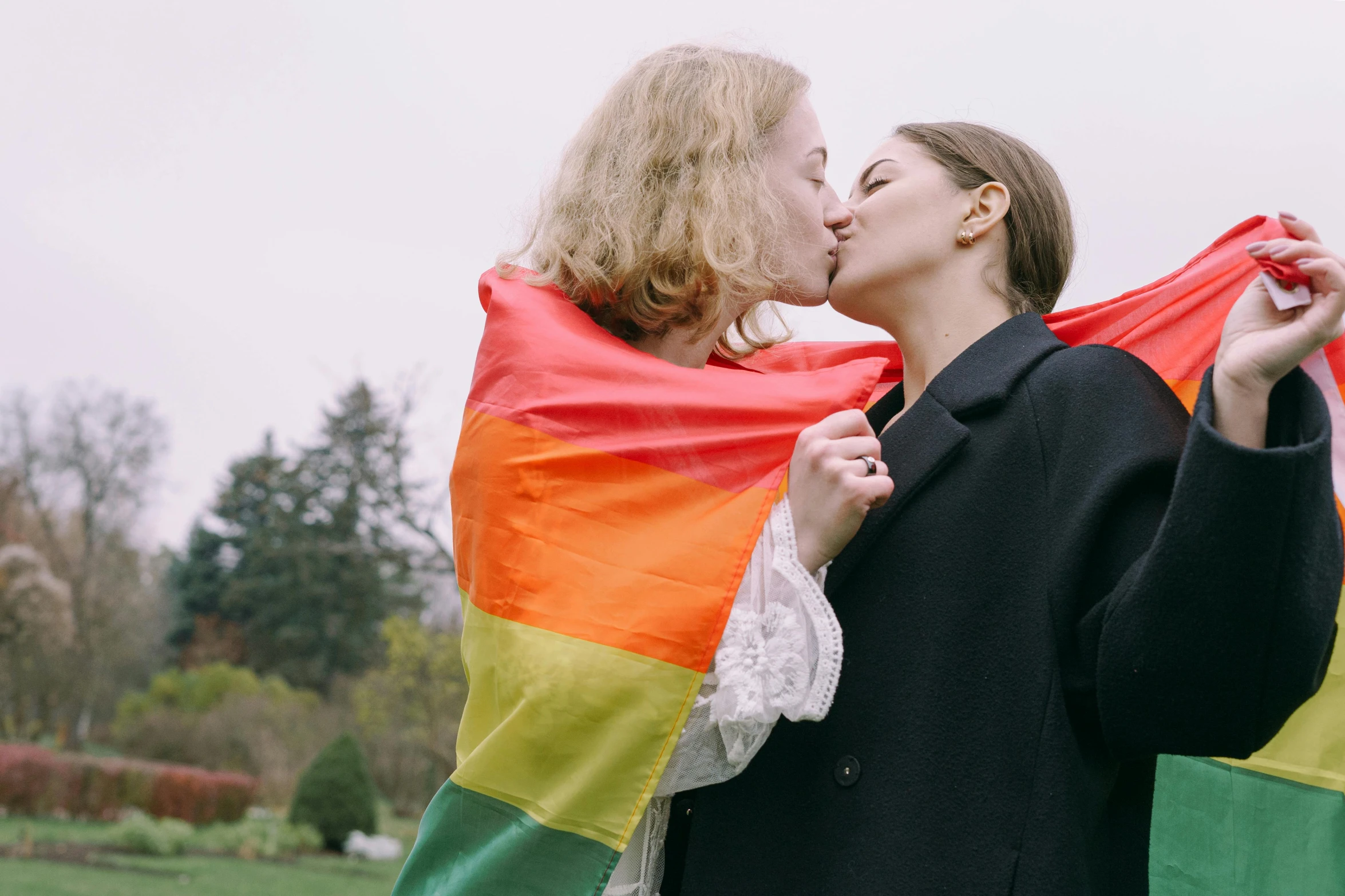 a woman kissing another woman while holding a flag