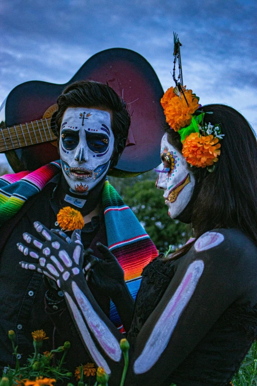 a man and woman with painted faces sitting in the grass