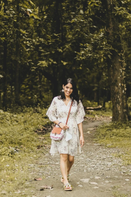 a lady in a dress is walking down a path