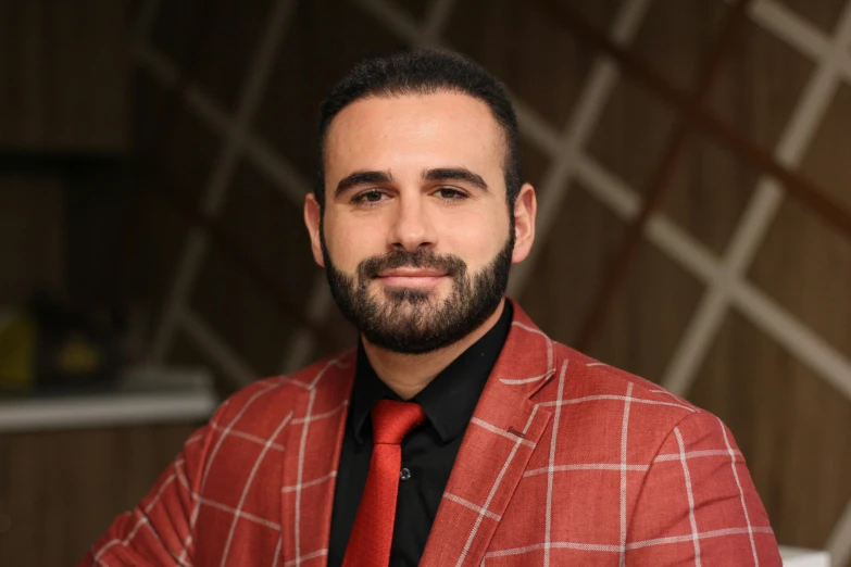 a bearded man wearing a red plaid suit and black tie