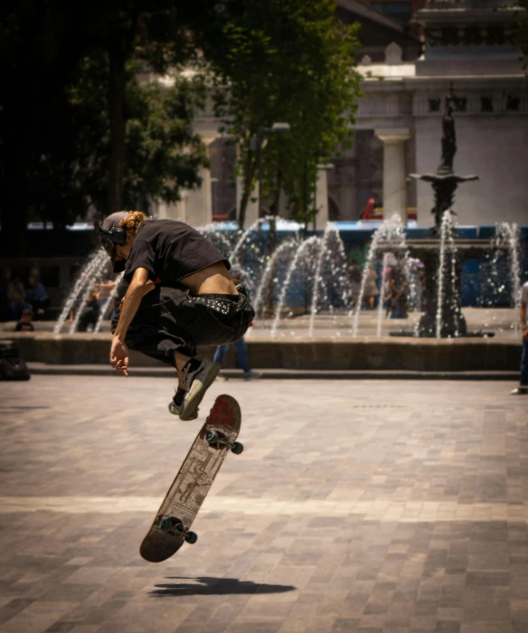 a skateboarder doing a trick in the air by a fountain