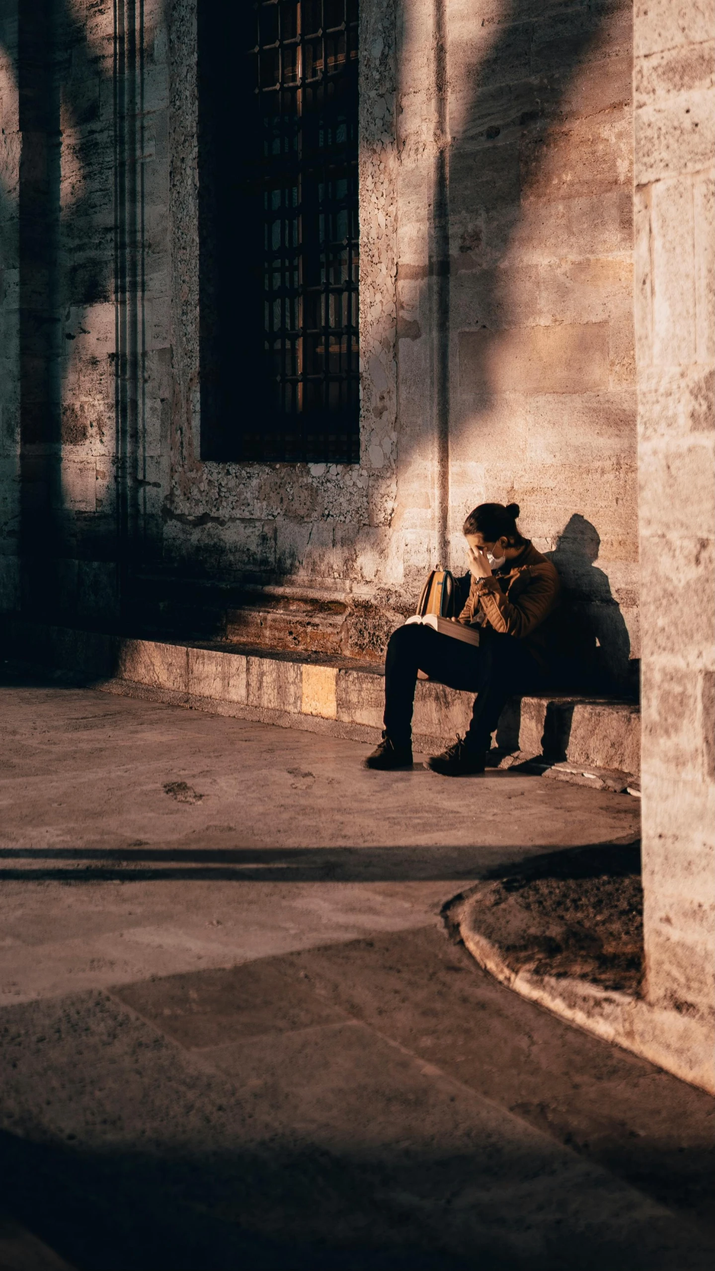 a person sitting on top of a bench in the sun