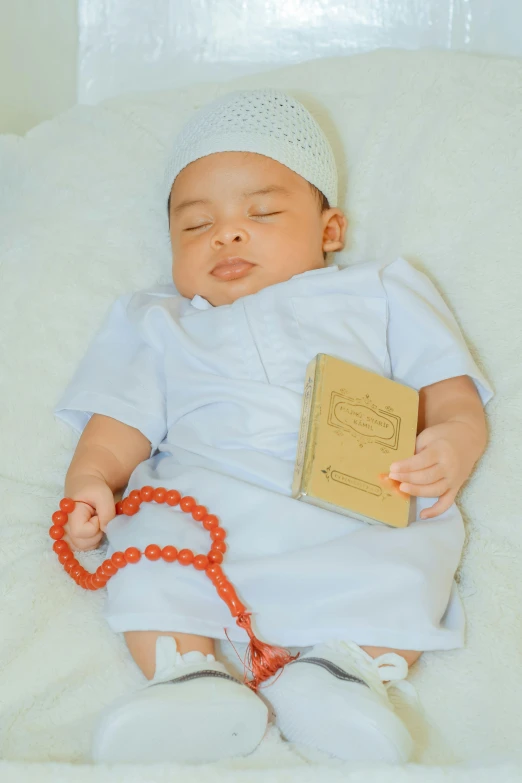 a baby wearing a white outfit and headband laying on top of a blanket