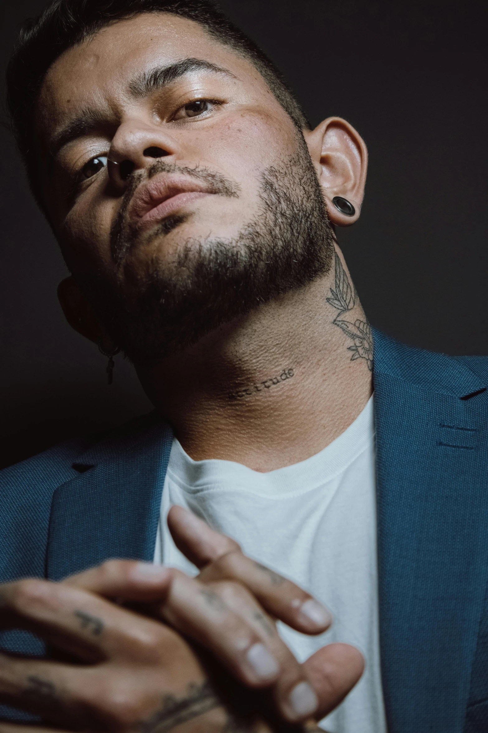 a man with tattoos on his chest wearing a blue jacket