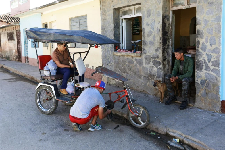 two men sitting next to a bike and a woman