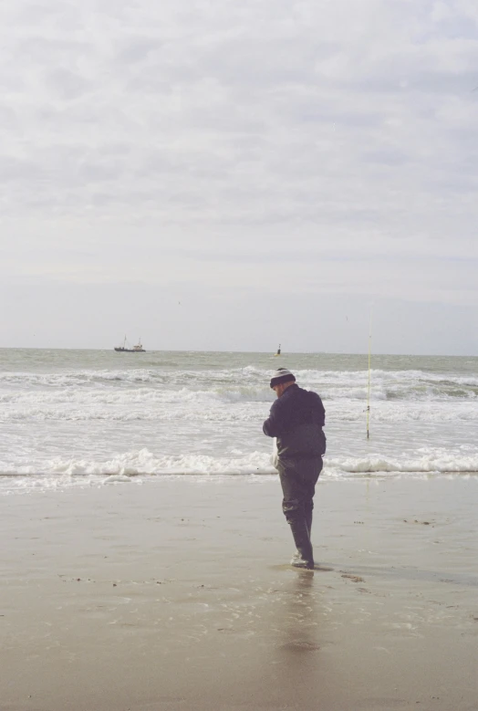 a man is standing on the beach near the ocean