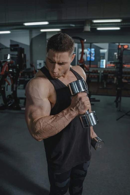 a bodybuilt man with a large arm standing in a gym