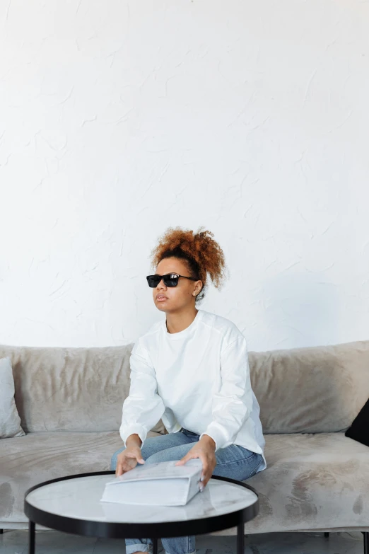 a woman sitting on top of a couch holding an open book