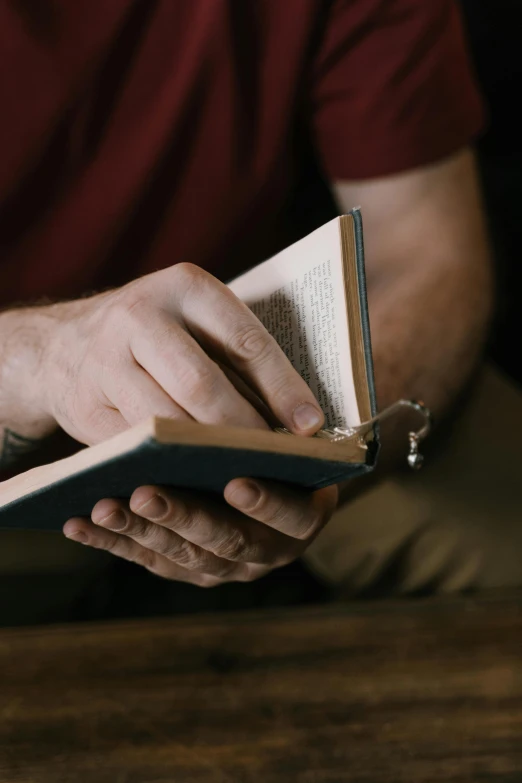 a man reading a book on top of a wooden table