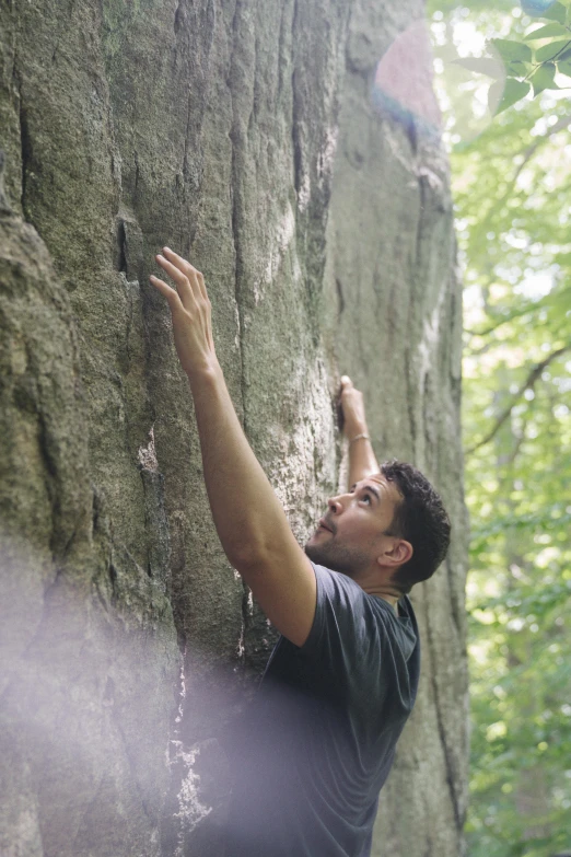 man climbing on rocks with trees in the background