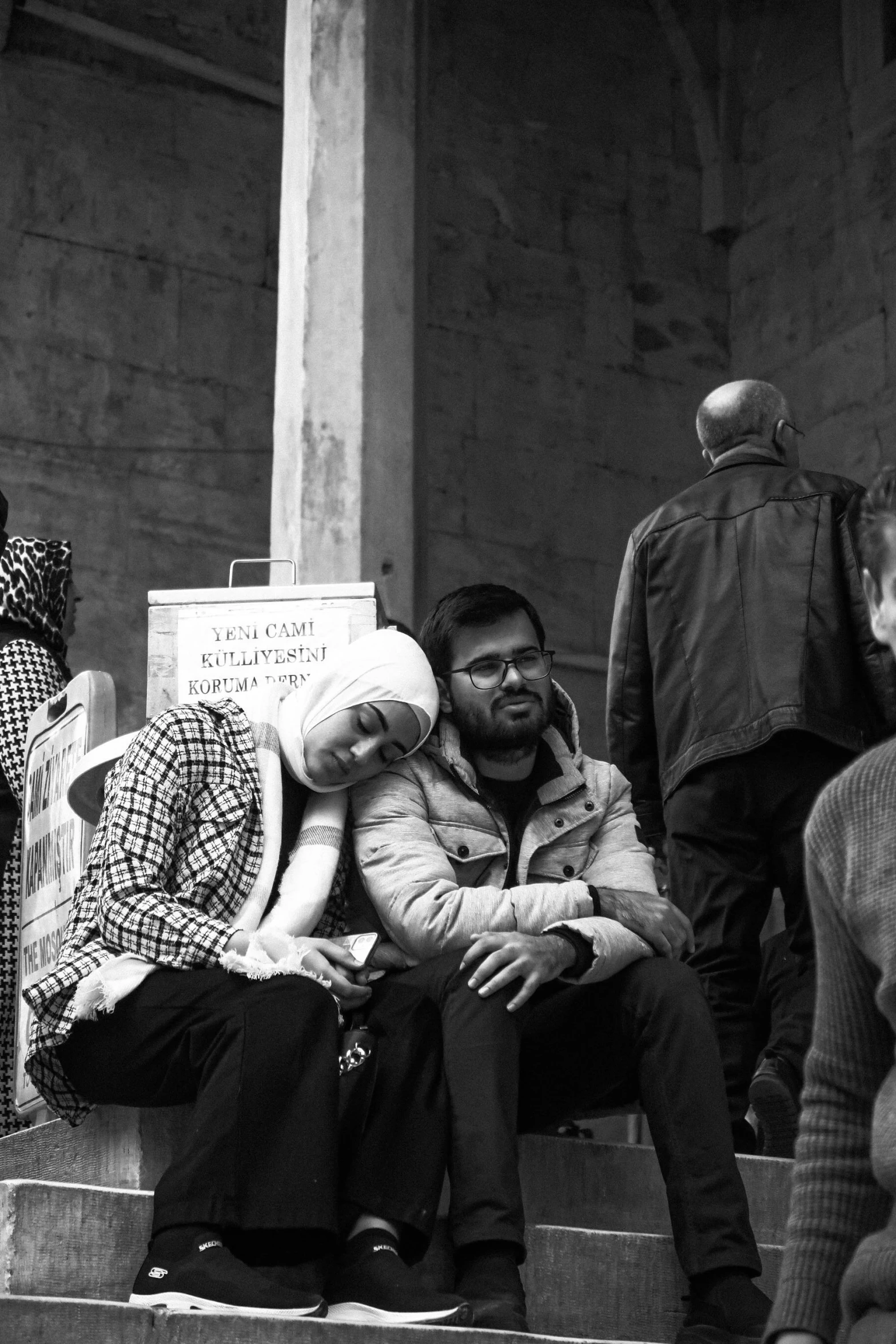 two people sit on the steps of the temple with a protest sign