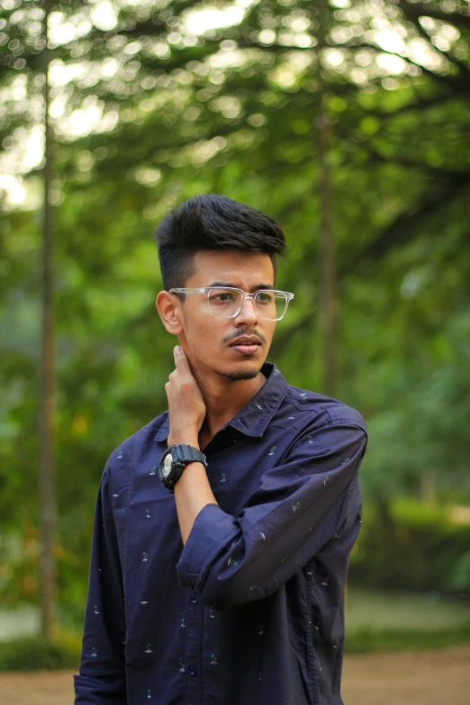 the young man is wearing glasses and standing outside