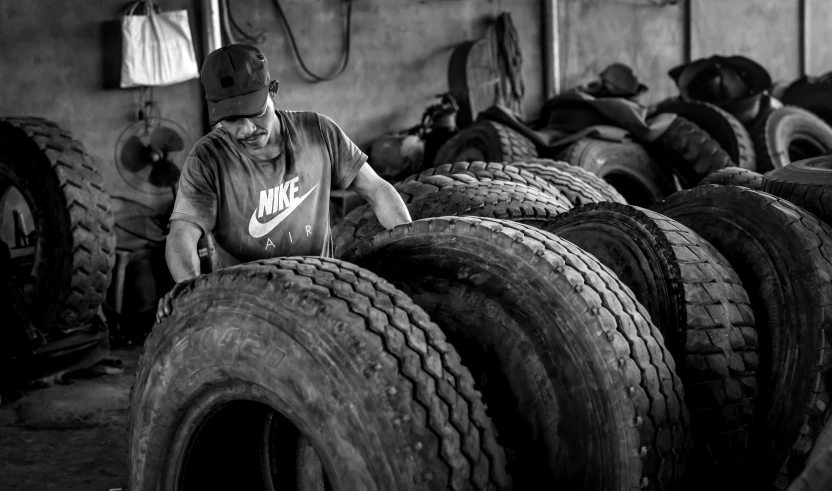 a man leaning on some tires in a factory