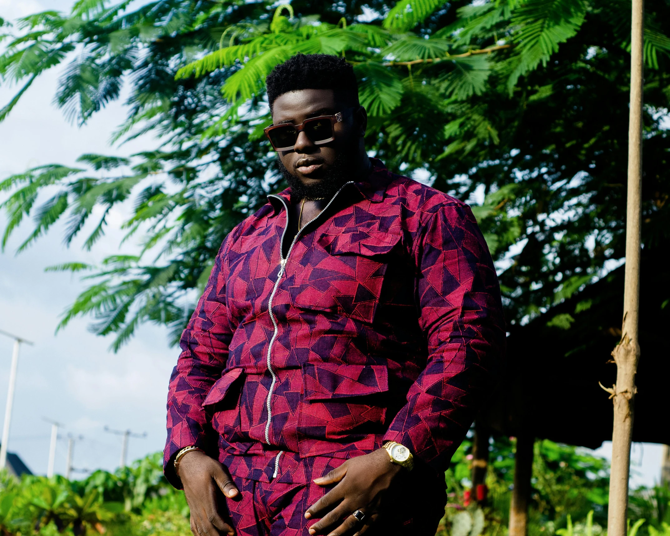 a man in an outfit poses by some palm trees