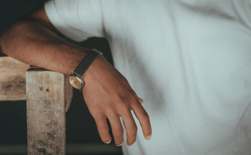 a man with an elegant watch is leaning on a chair