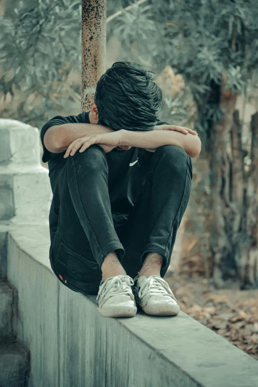 a man with head bowed sitting on the wall