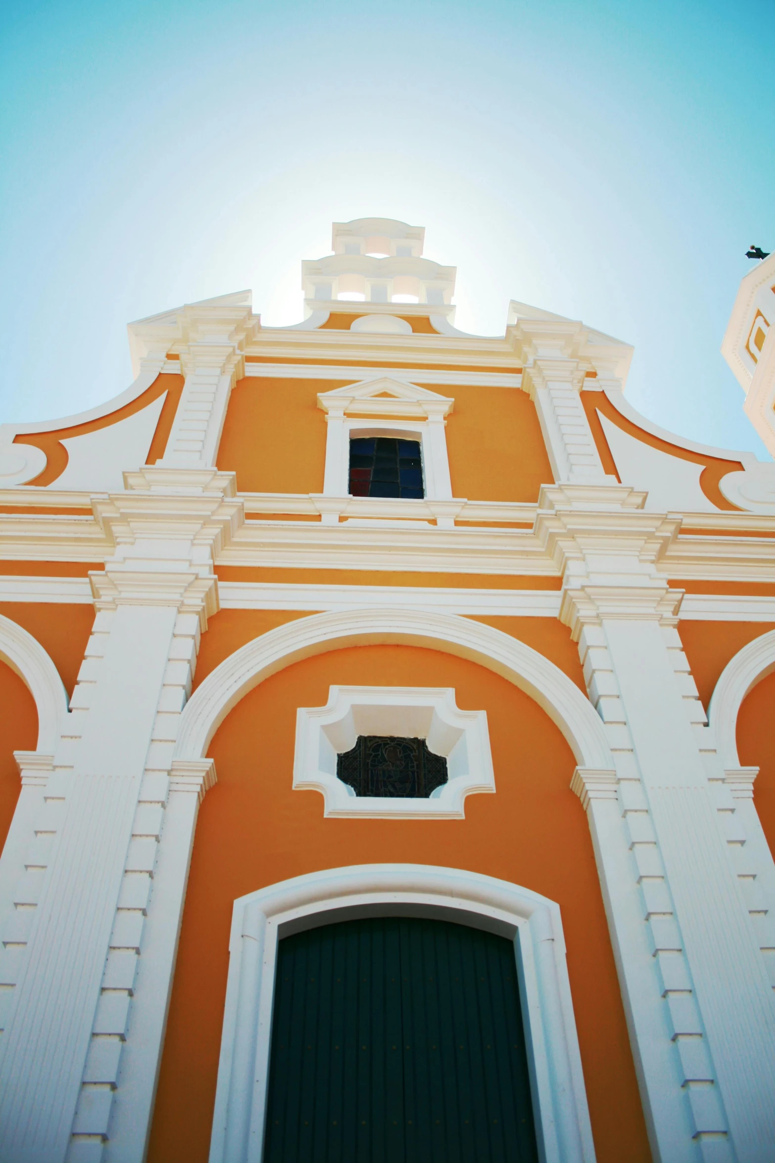 a bright orange building with a steeple and green door