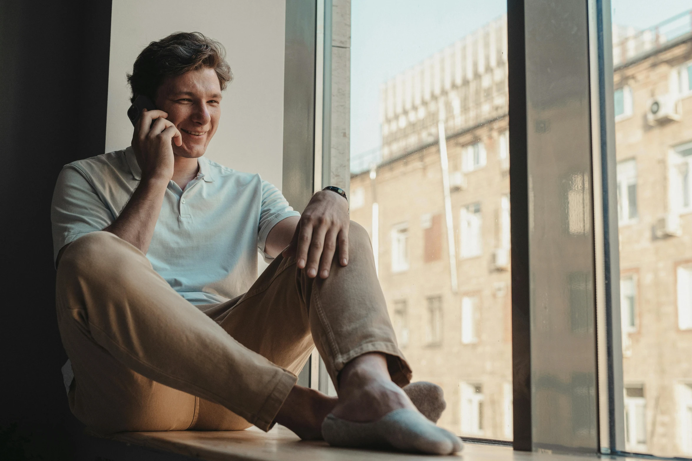 a man with his foot in the window while talking on a cell phone