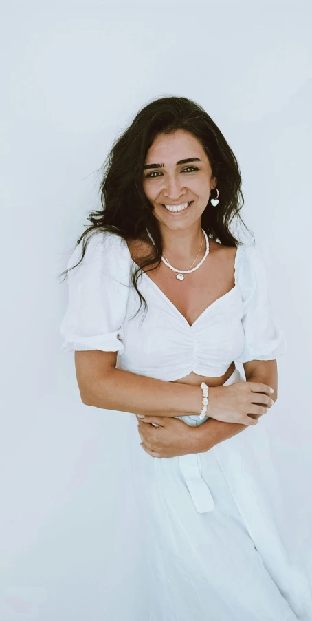 woman with black hair wearing a white dress and a pearl necklace