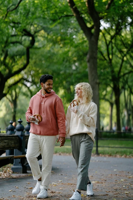 man and woman walking through park while talking