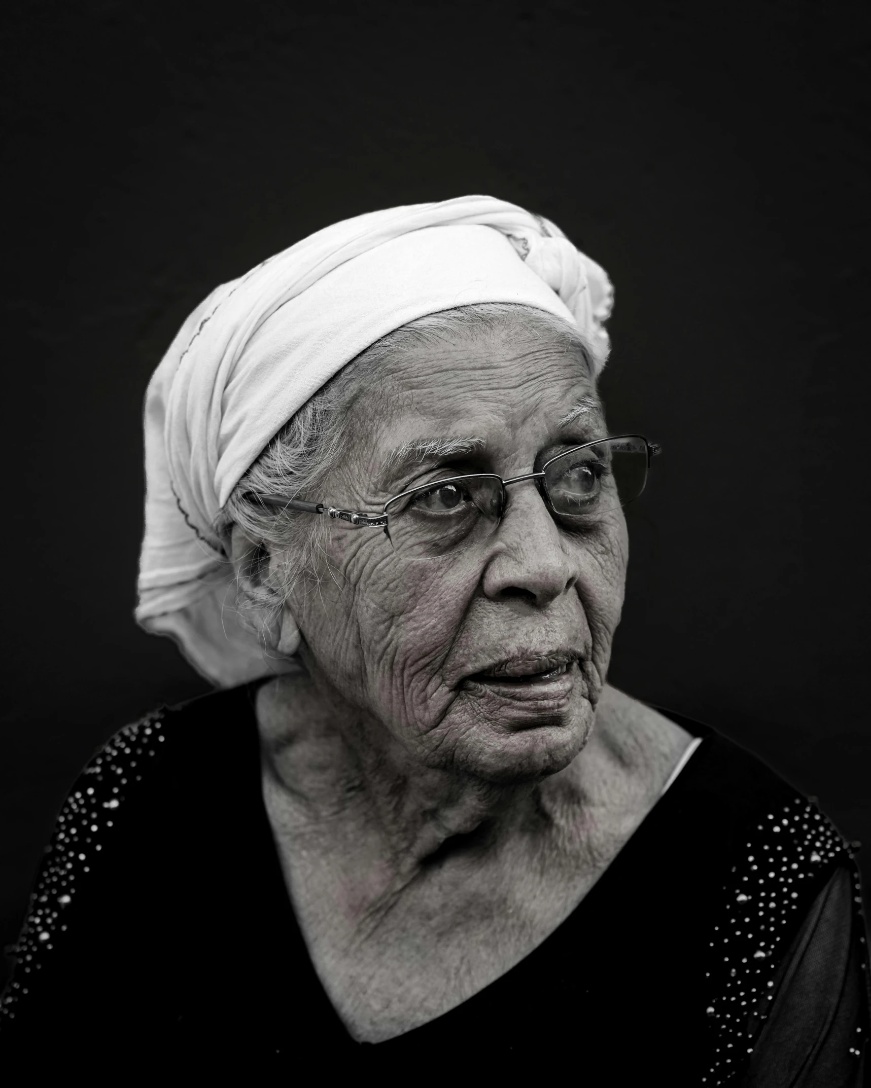 an old woman with glasses and a white head scarf on