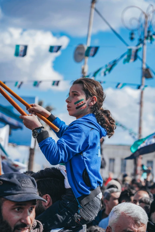 a girl carries soing with both hands while holding a wooden stick