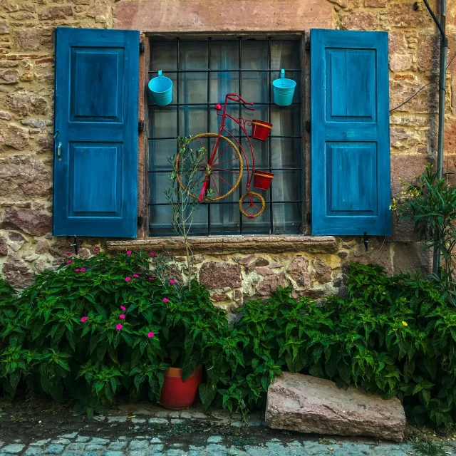 an old building with blue shutters and a window filled with flowers