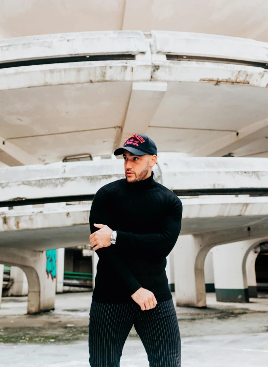 a man wearing a hat and all black stands in a street