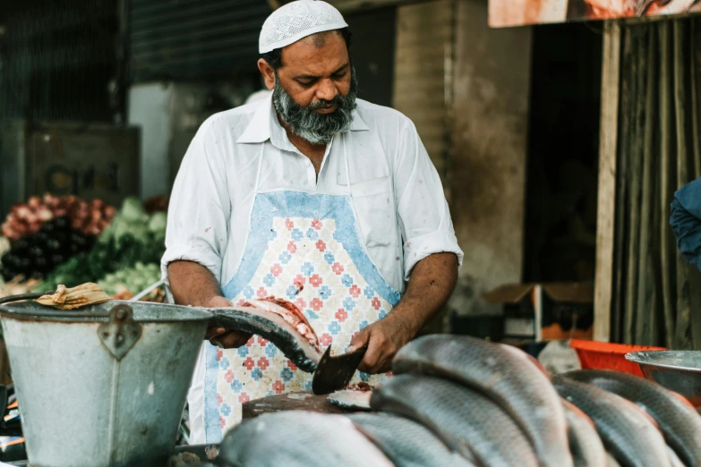 a man wearing an apron cuts fish into pieces