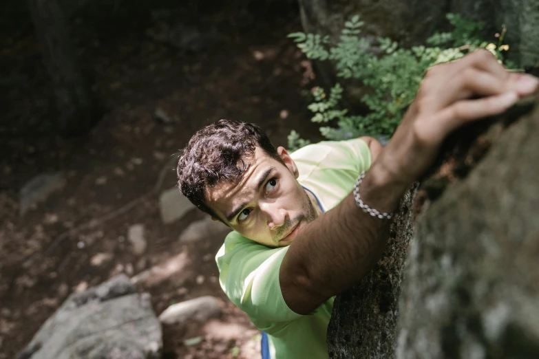 a boy in a green shirt climbing on a rock