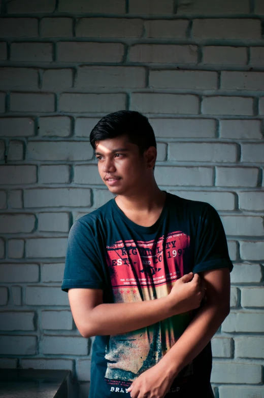 a man stands in front of a brick wall