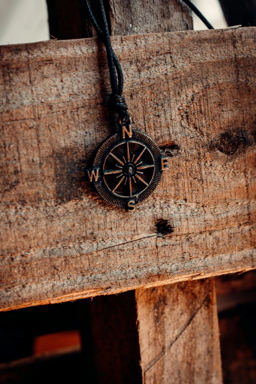 the compass is laying on the wood next to the string