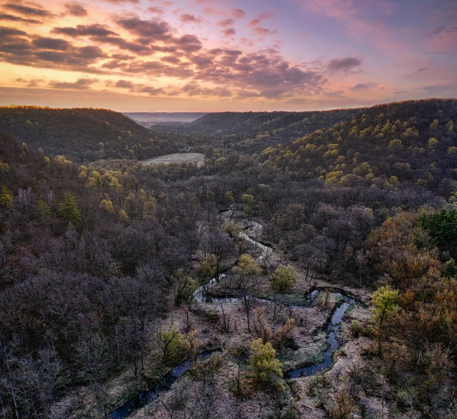 a sun set over a valley with small river