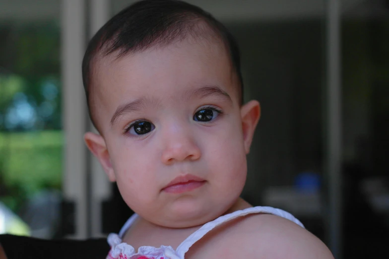 a young baby sitting and looking at the camera