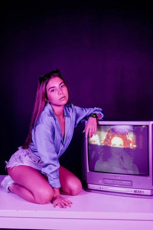 a girl sitting on the table while playing an old tv