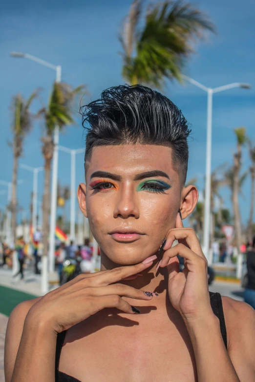 a woman is posing at the beach with green and pink eye makeup