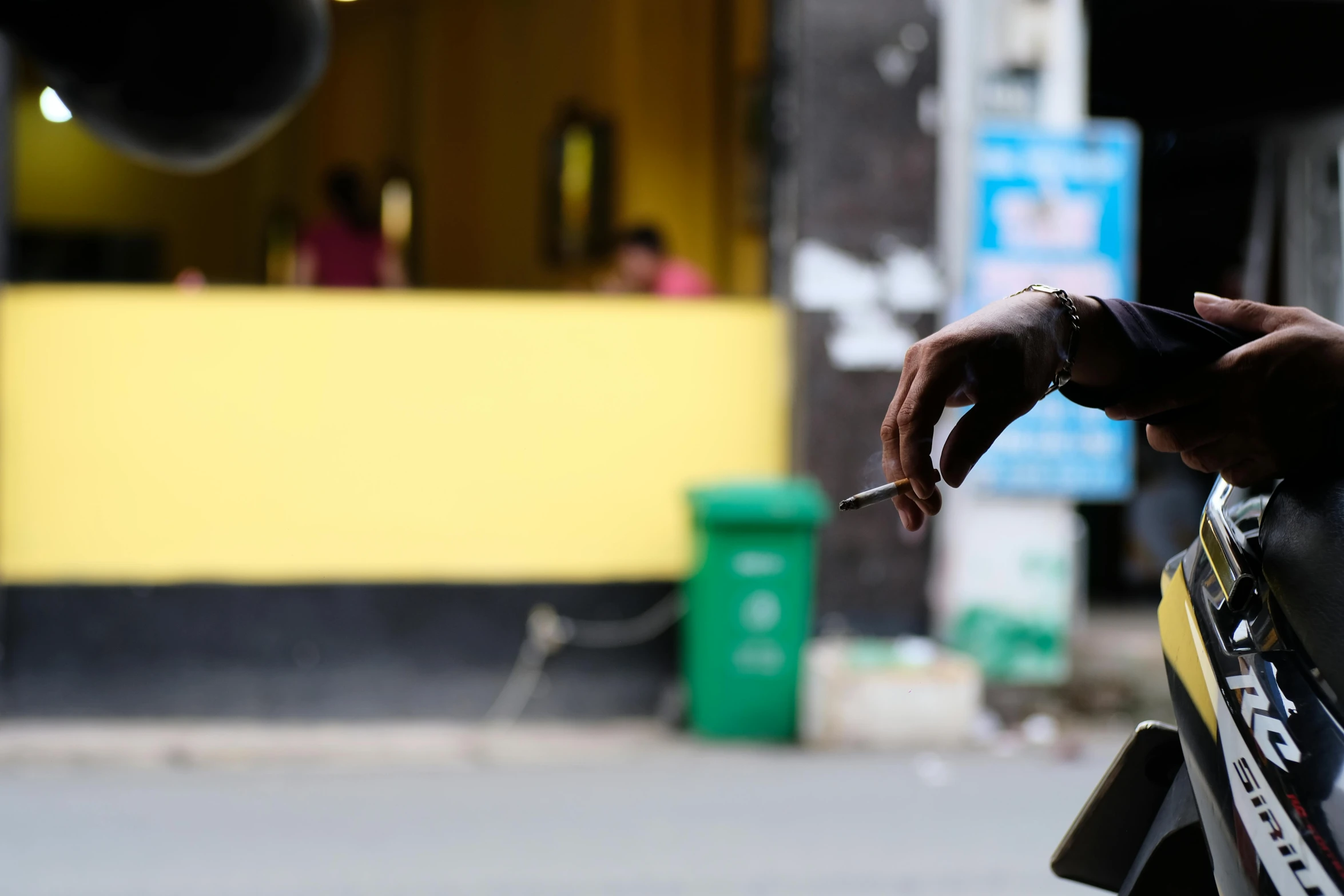 a person smoking a cigarette on the side of a street