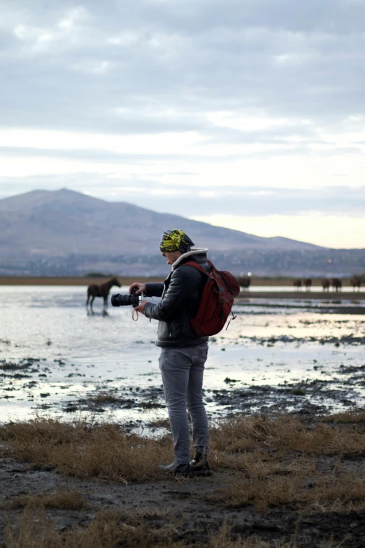 a man taking a po of horses at the waters edge