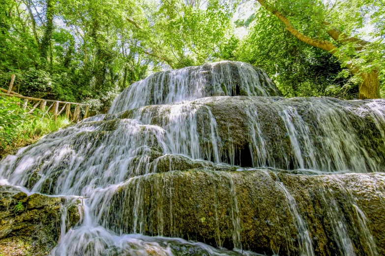 a tall waterfall surrounded by greenery on a sunny day