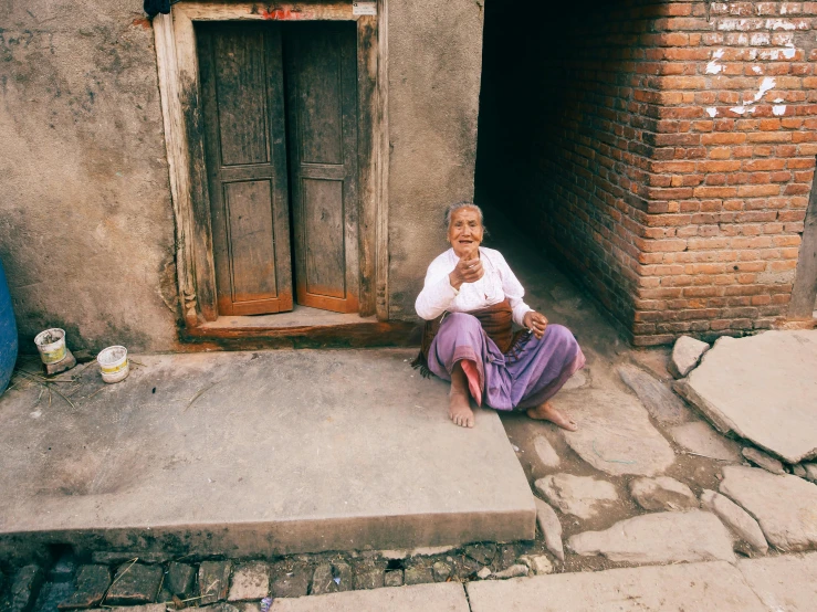 an old woman in a purple dress sits on steps